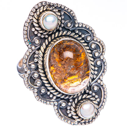 Silver oval gemstone ring with ornate metalwork and two white iridescent cabochons