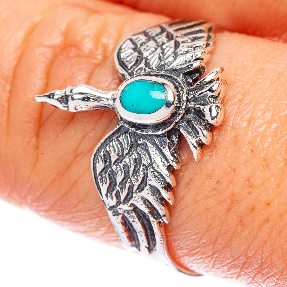 Silver bird ring with turquoise oval cabochon, feathered design on finger