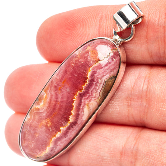 Oval rhodochrosite pendant with pink, red, and gold banding in sterling silver bezel