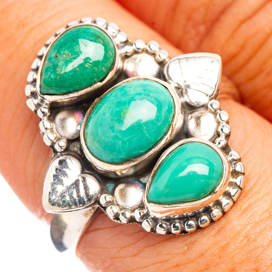 Sterling silver turquoise ring on finger with three green oval stones and raised settings