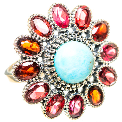 Oval light-blue cabochon ring with surrounding red faceted stones in silver setting