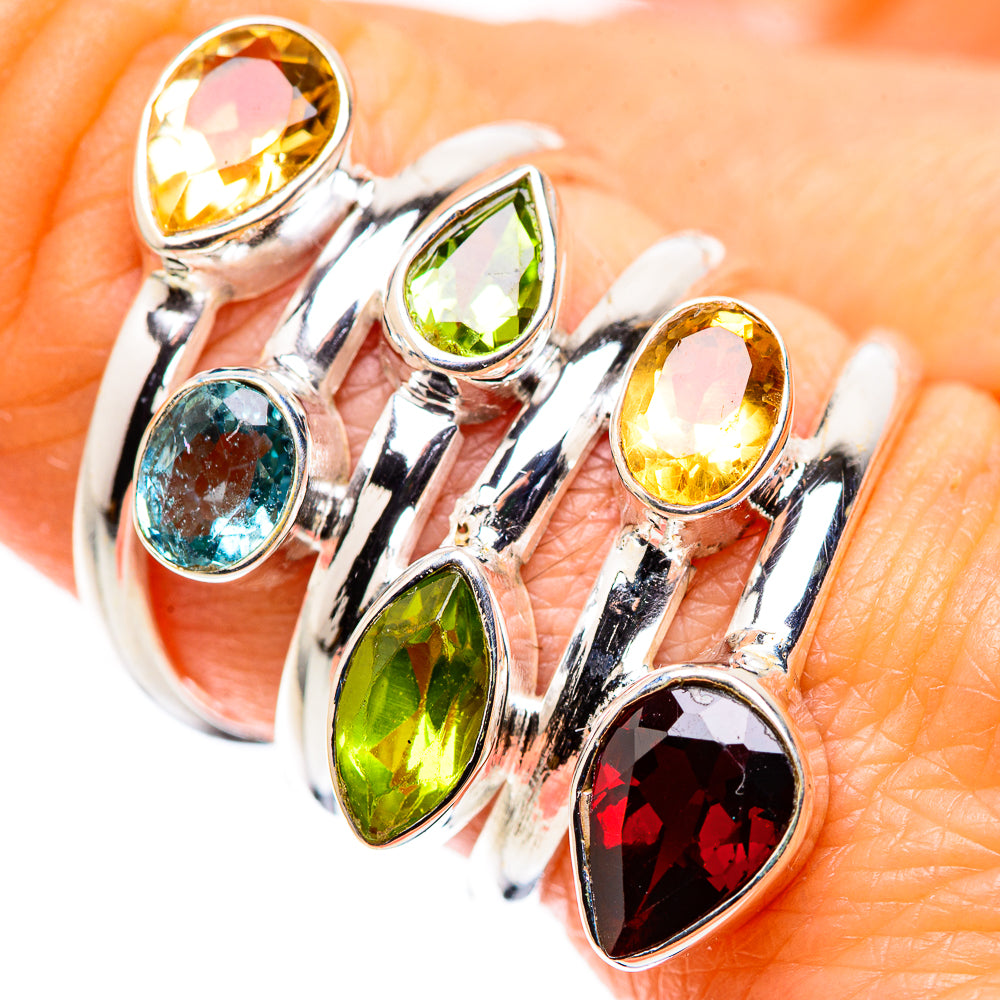 Silver multi-stone ring with yellow, green, blue, and red oval gems on finger