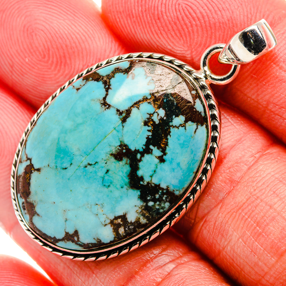 Oval turquoise gemstone pendant with ornate silver bezel and top bail