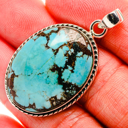 Oval turquoise gemstone pendant with ornate silver bezel and top bail