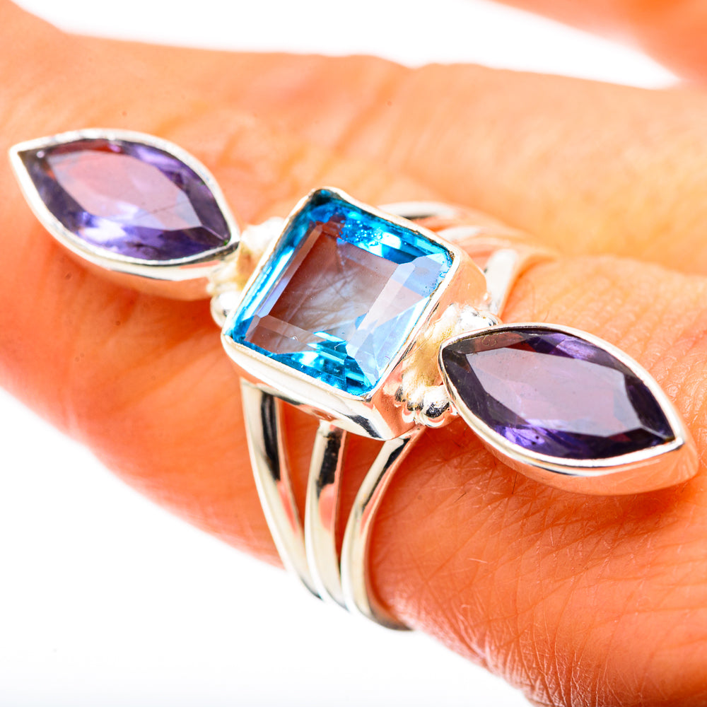 Silver-tone ring worn on hand, with square blue and two marquise purple gemstones