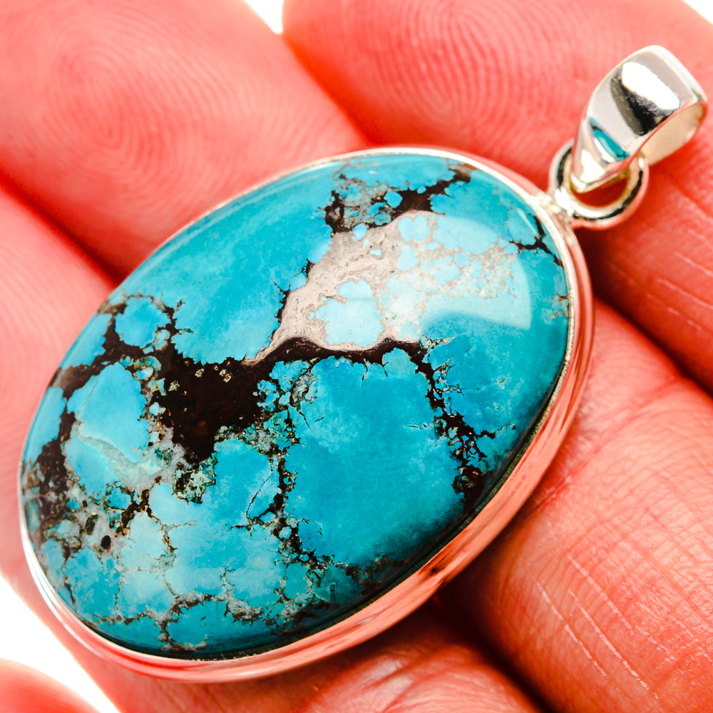 Oval turquoise gemstone pendant with black matrix, set in silver bezel and bail