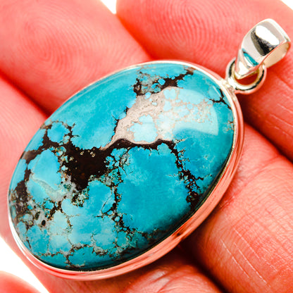 Oval turquoise gemstone pendant with black matrix, set in silver bezel and bail