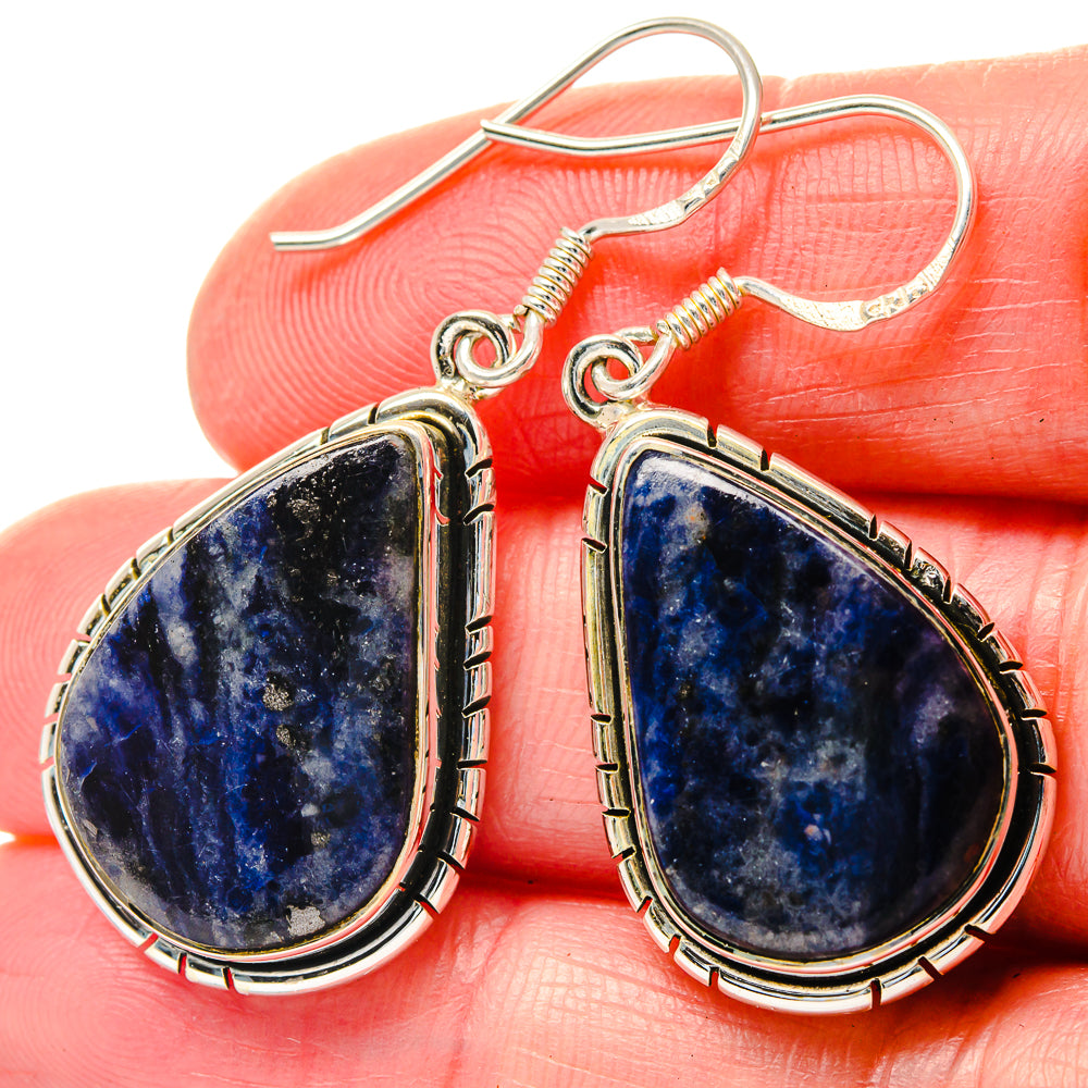 Blue sodalite teardrop earrings with sterling silver wire bezel and fishhook on hand.