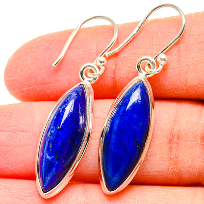 Lapis lazuli earrings with oval blue stones and sterling silver hook backs, close-up.