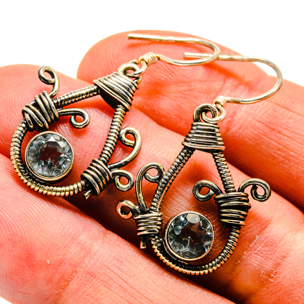 Gold-tone blue gemstone drop earrings with ornate wirework and dangling hooks