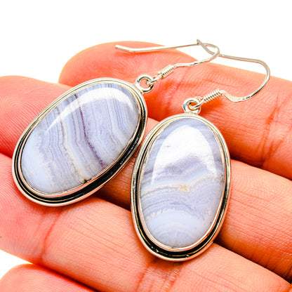 Oval blue lace agate earrings on hook settings, shown on fingertip close-up