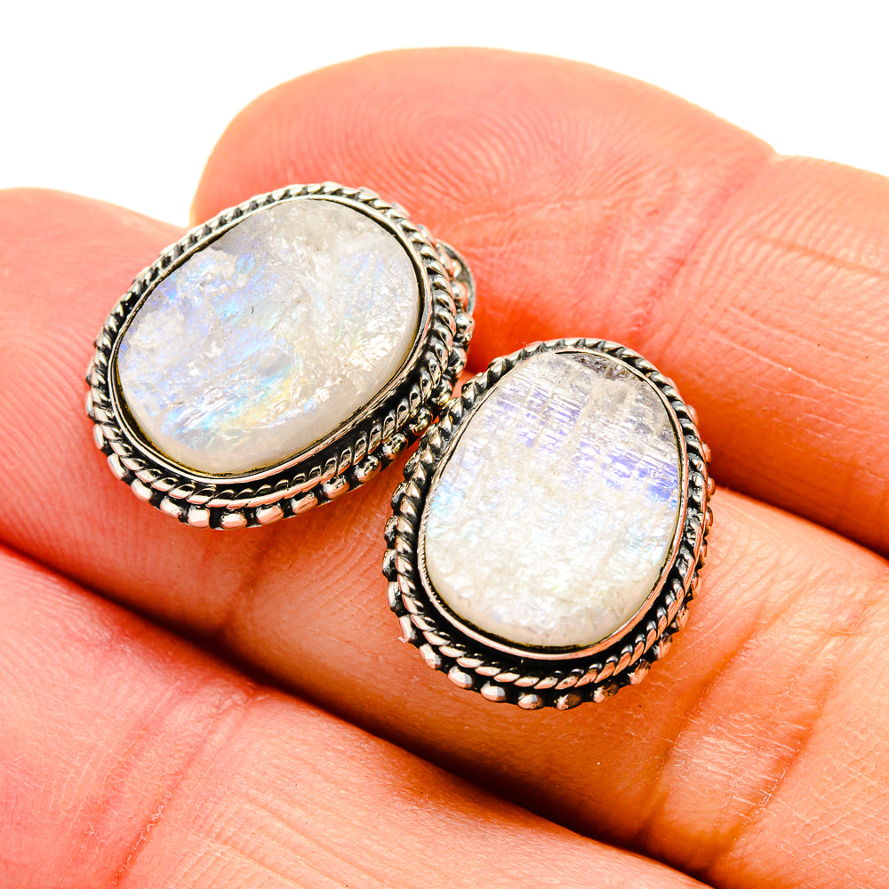 Iridescent oval moonstone earrings on fingers, ornate silver rope bezel
