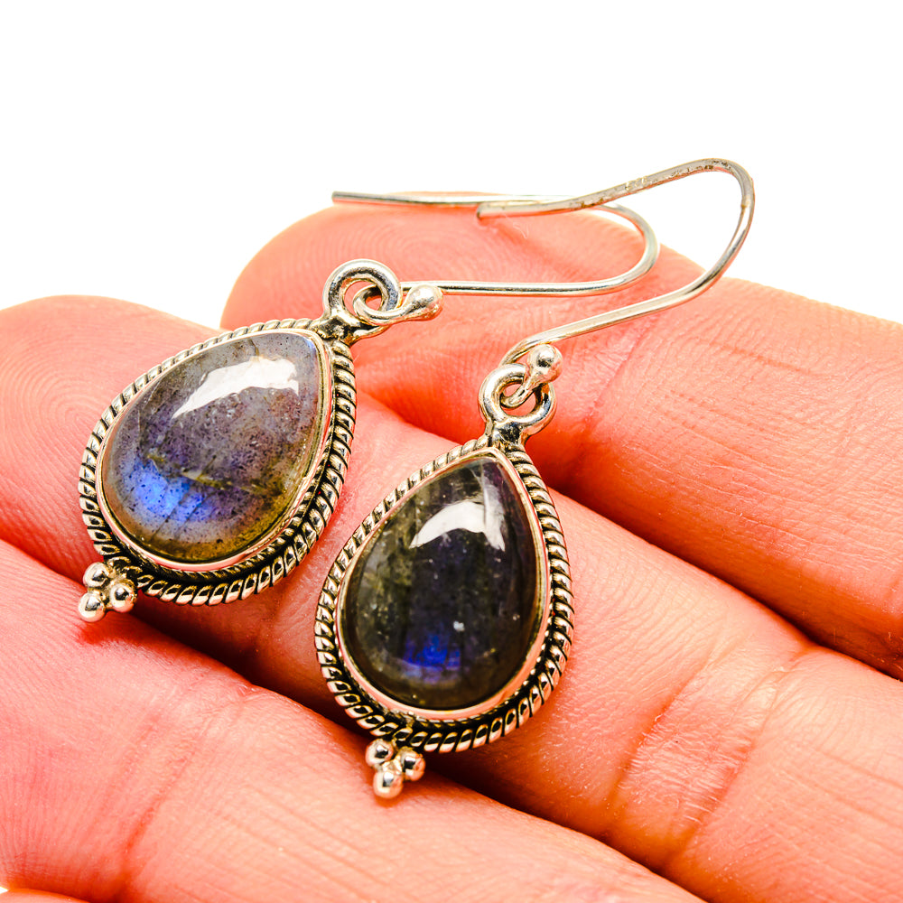 Labradorite teardrop earrings on gold-tone frames, close-up with blue-purple stone flash.