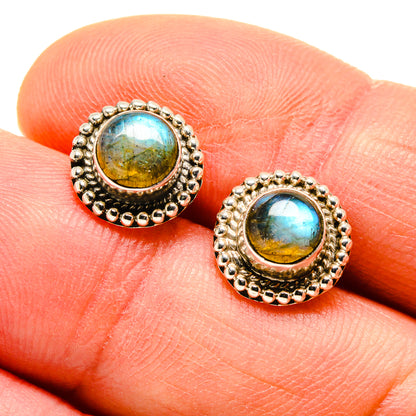 Close-up of oval labradorite stud earrings in ornate silver bezels