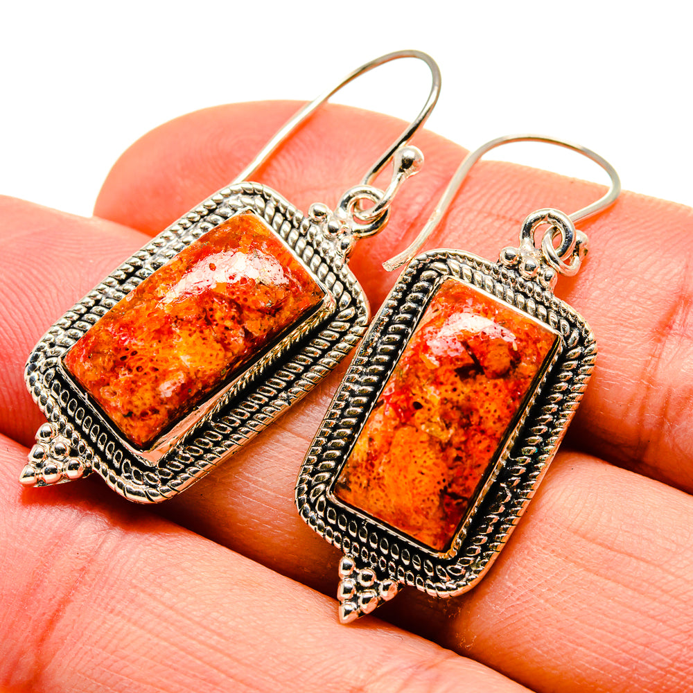 Rectangular coral earrings close-up, orange stones in textured silver borders on hooks