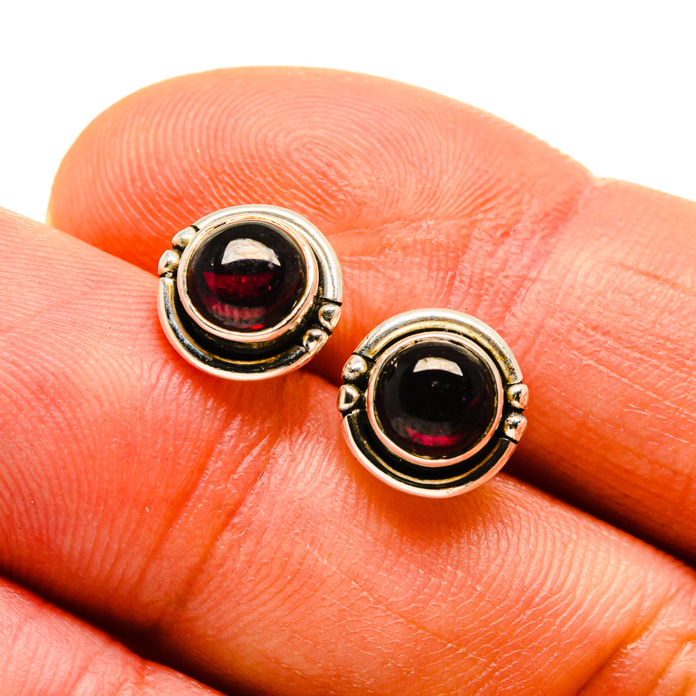 Sterling silver stud earrings with round garnet-red gemstones, bezel and scalloped trim