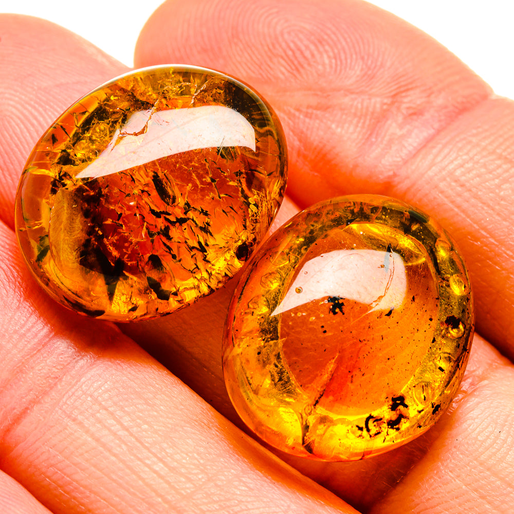 Amber teardrop stud earrings with golden bezels and natural inclusions on skin