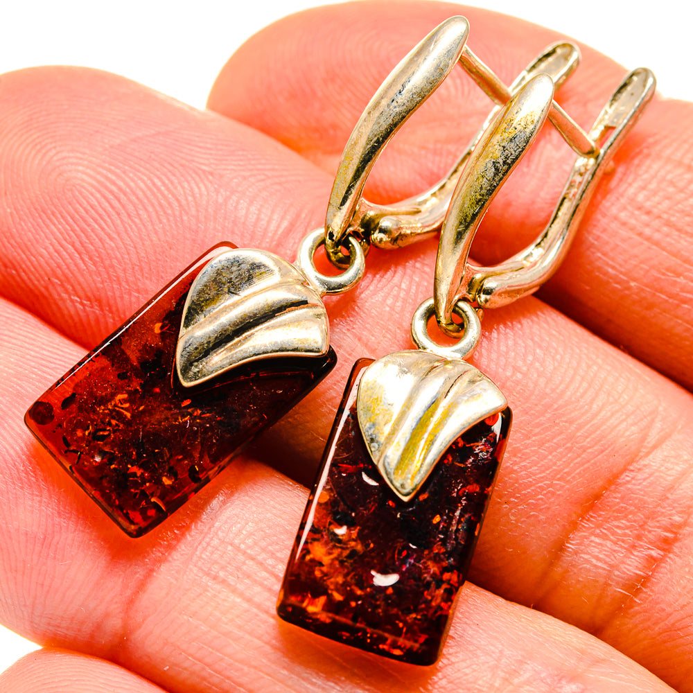 Close-up of gold-tone hoop earrings with amber rectangular dangles