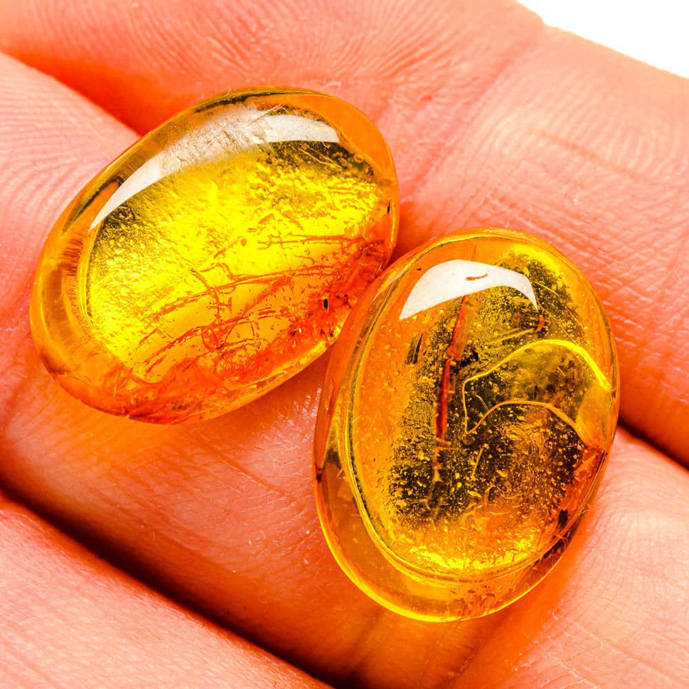 Close-up of oval amber cabochon stud earrings with gold-tone edges
