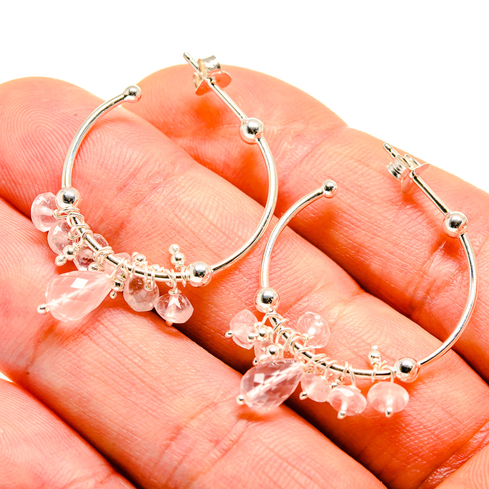 Closeup of silver hoop earrings with pink gemstone drop fringe