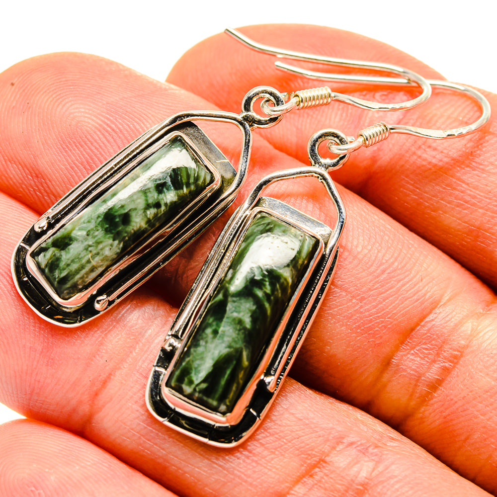 Rectangular seraphinite earrings on hand, green marbled stone in silver frames with hooks