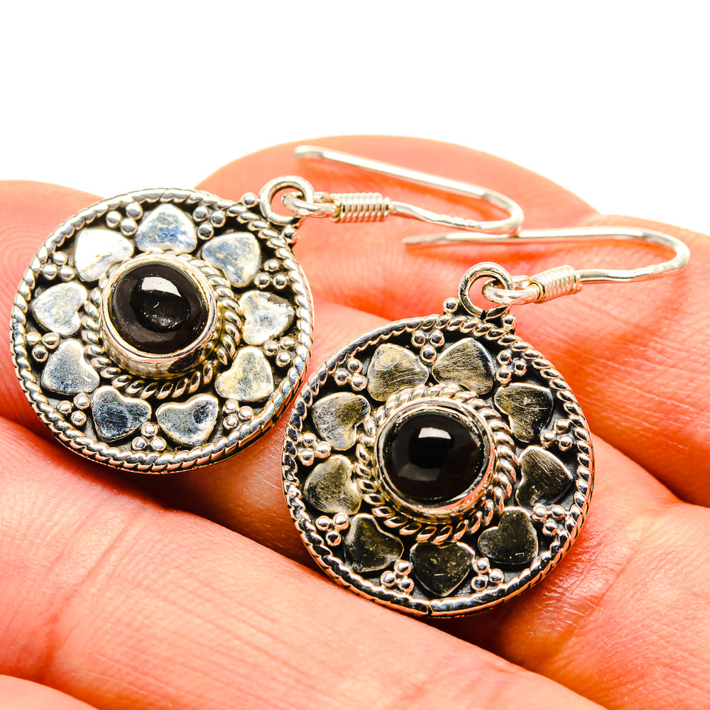 Sterling silver onyx earrings close-up, oval round frame with black gemstone and hook backs