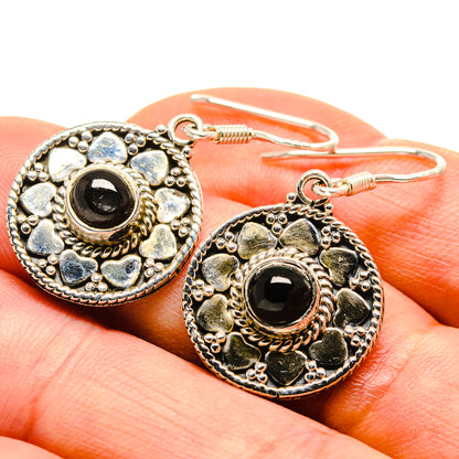 Sterling silver onyx earrings close-up, oval round frame with black gemstone and hook backs