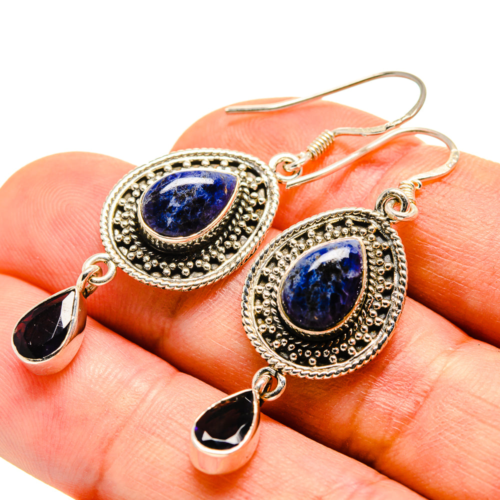 Round blue stone earrings with ornate halos, teardrop charms, and hooked backs