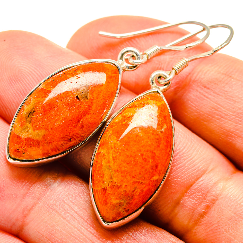 Sponge coral drop earrings on hand, oval orange stones with speckled texture and metal hooks