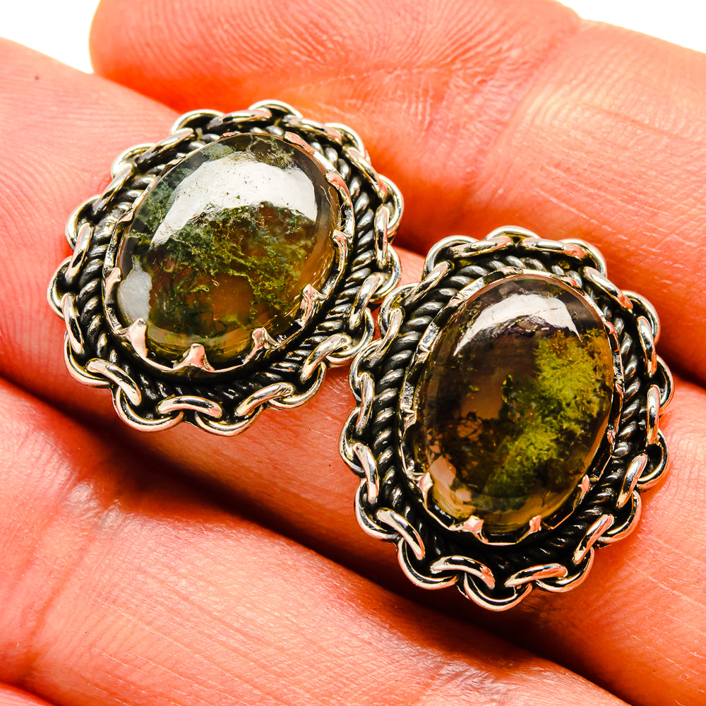 Green moss agate oval stud earrings on hand, silver-tone braided frame