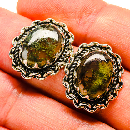 Green moss agate oval stud earrings on hand, silver-tone braided frame