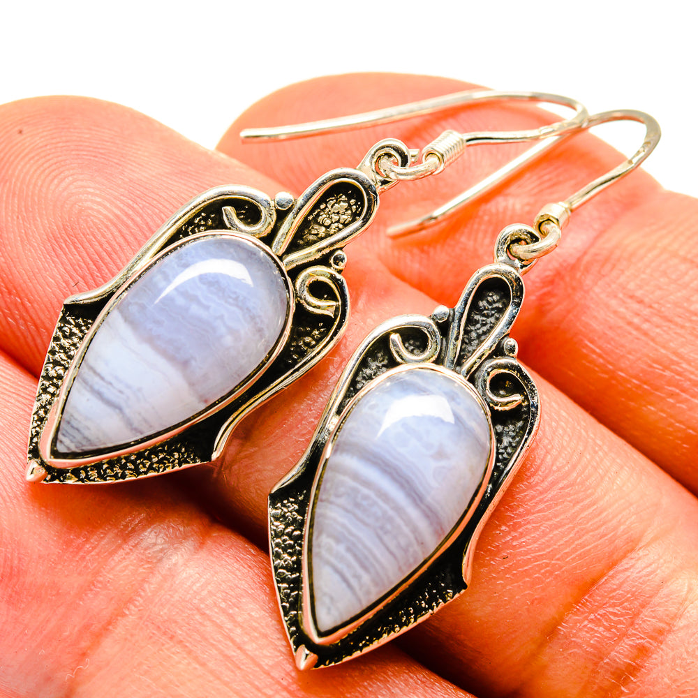 Teardrop stone earrings with black filigree frame and iridescent white sheen