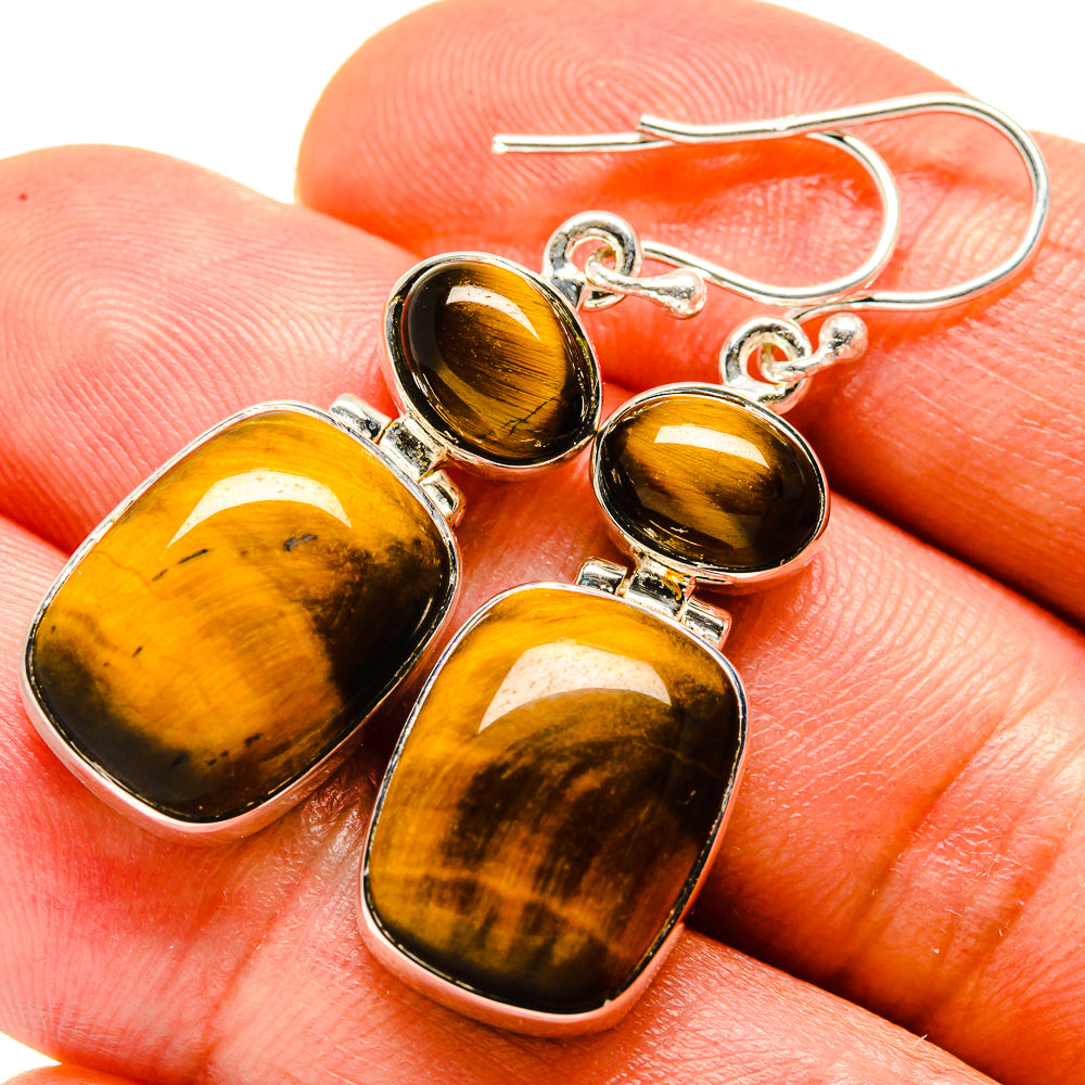 Tiger eye drop earrings with silver hooks and amber-brown tiger-eye stones, close-up
