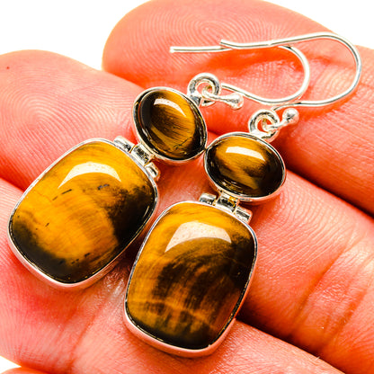 Tiger eye drop earrings with silver hooks and amber-brown tiger-eye stones, close-up
