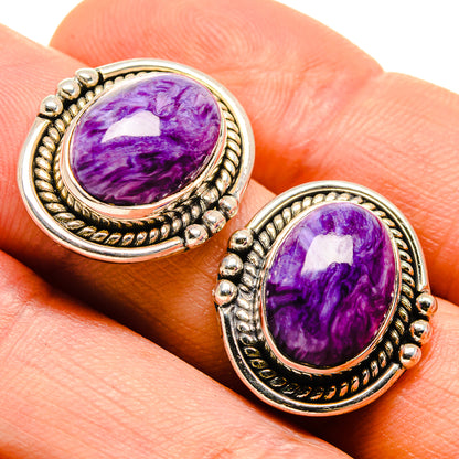 Oval purple cabochon earrings with gold-tone filigree settings and small bead details.