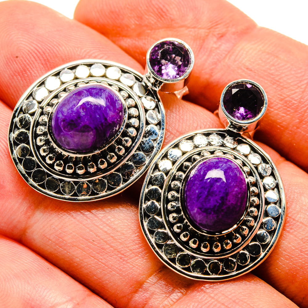 Charoite and amethyst earrings close-up: purple cabochon rounds with blue-stone border, silver-tone