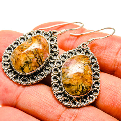 Teardrop butterfly jasper earrings with ornate silver border, shown close-up on hand