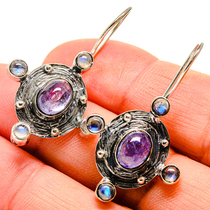 Silver-tone oval drop earrings with purple tanzanite center and blue moonstone halos, lever hooks
