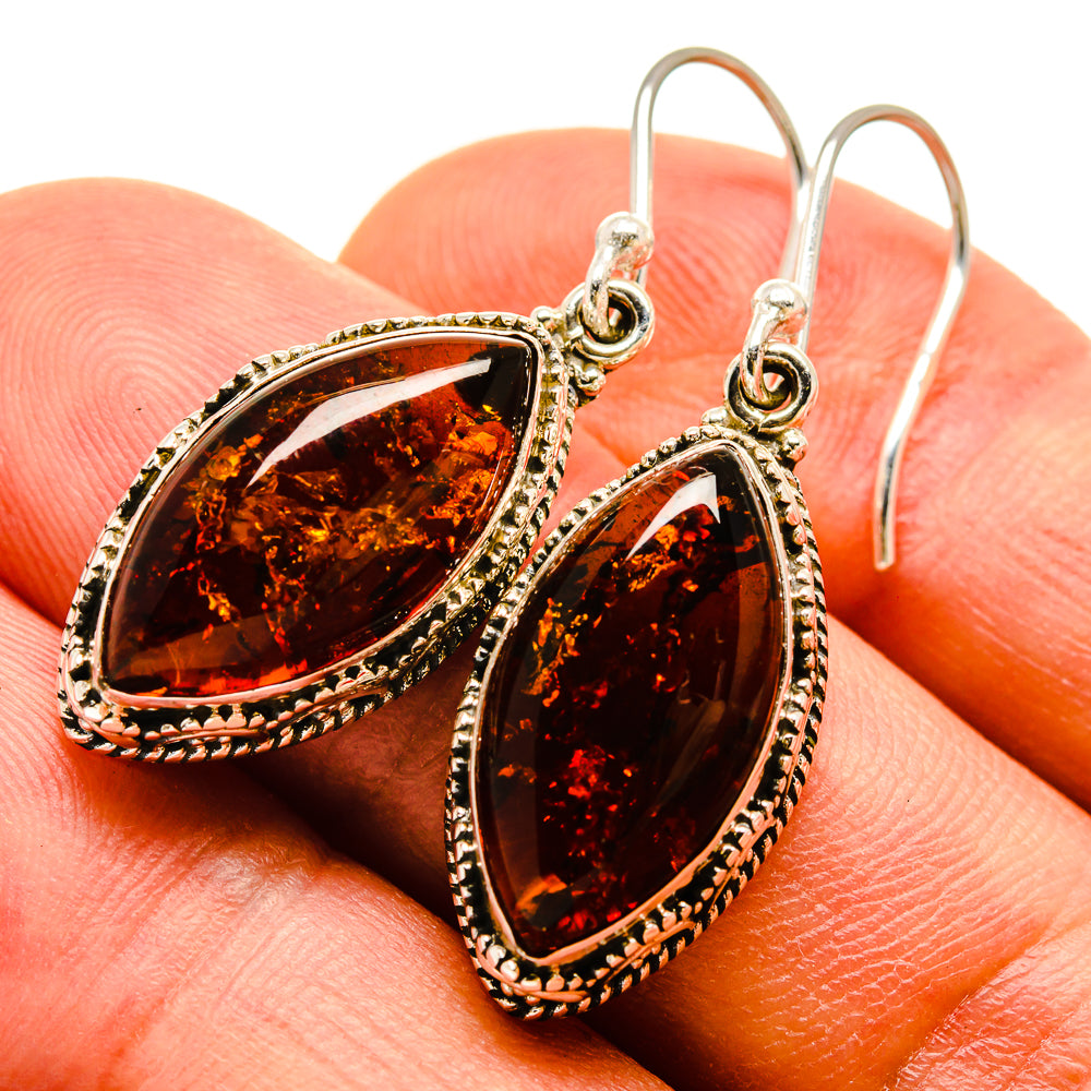 Teardrop amber earrings in tarnished silver setting, fishhook style, close-up view