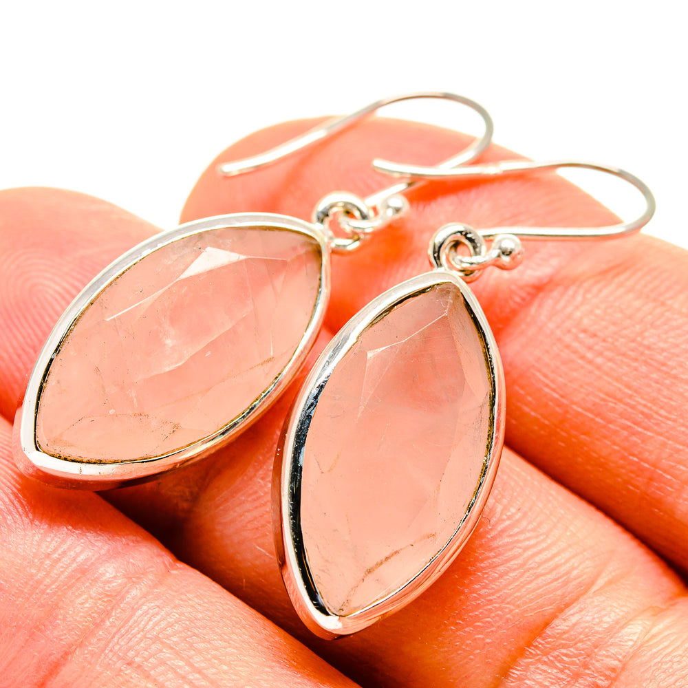 Rose quartz oval drop earrings with silver bezel and hooked ear wires on fingers