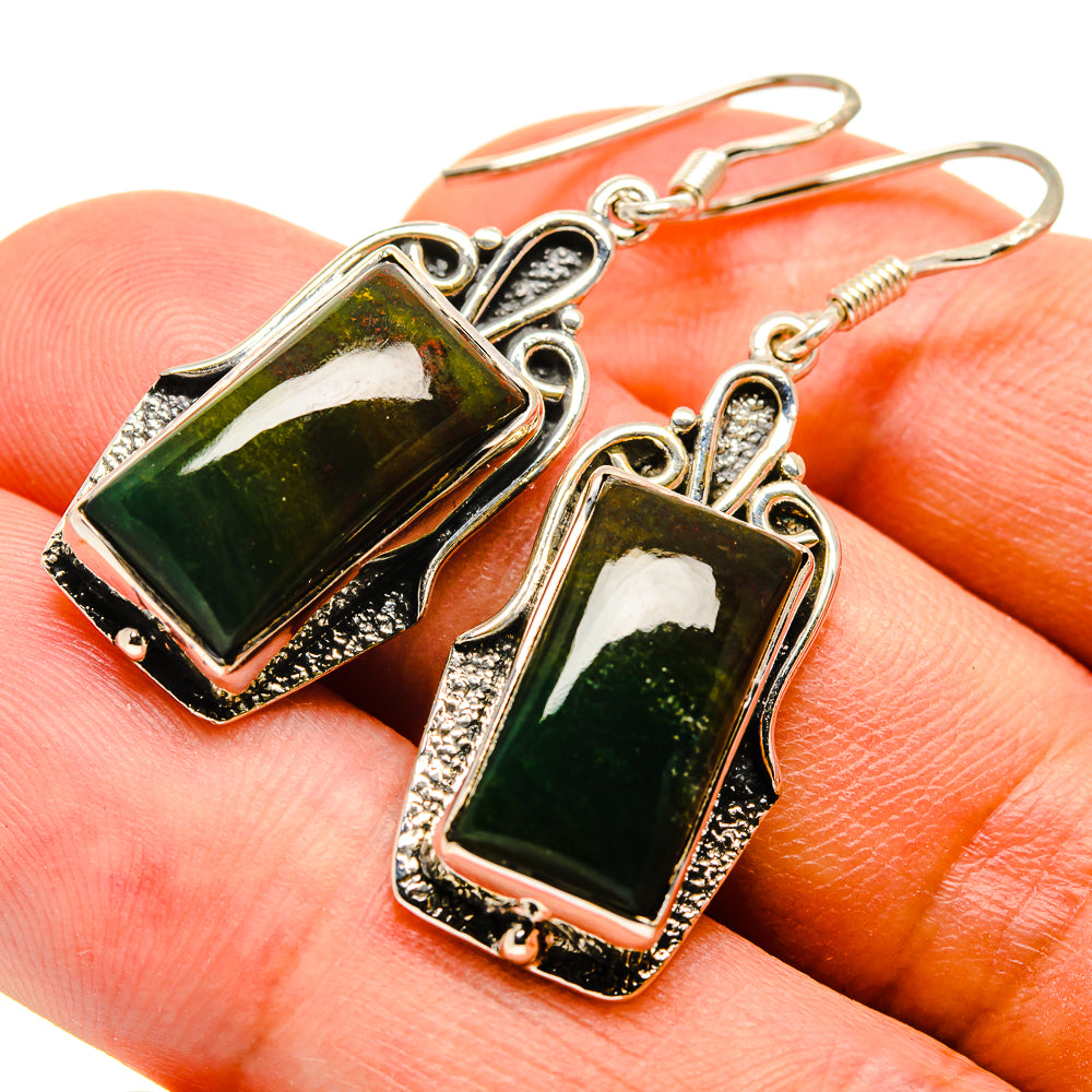 Sterling silver earrings with dark green rectangular stones in ornate bezel, close-up