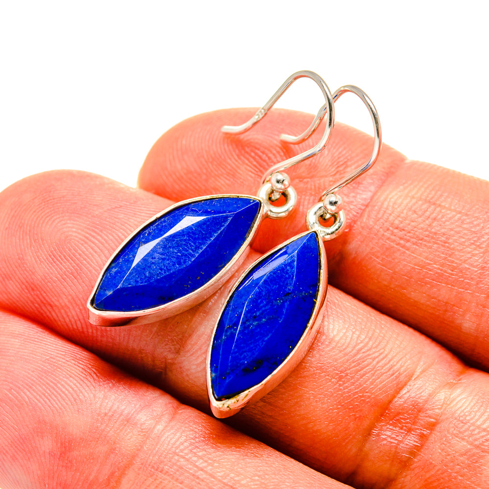 Lapis lazuli drop earrings on gold-tone hooks with blue pear-shaped stones, close-up