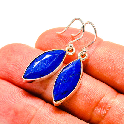 Lapis lazuli drop earrings on gold-tone hooks with blue pear-shaped stones, close-up