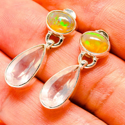Closeup of amber oval stud earrings with dangling teardrop clear stones and silver hooks