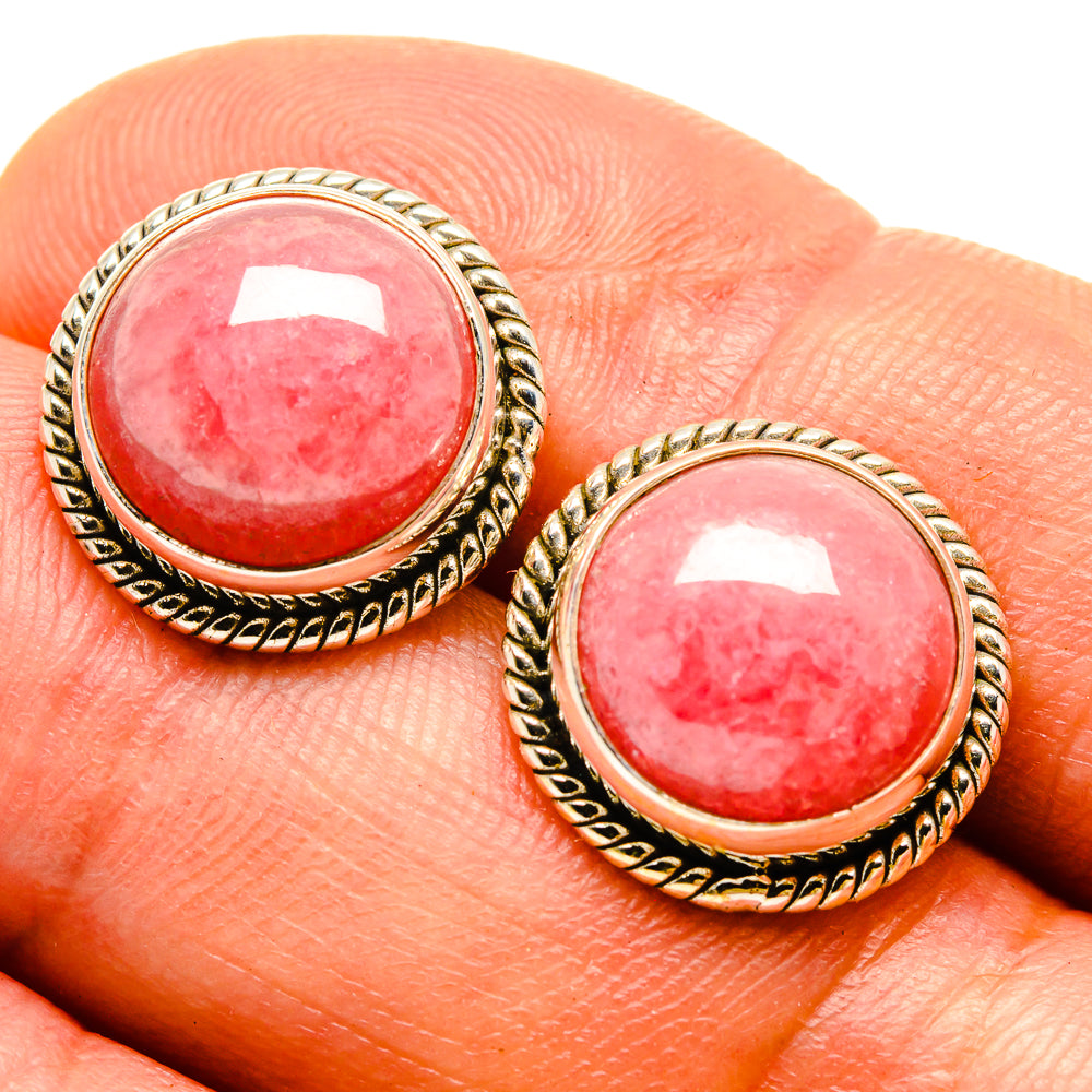 Close-up of oval rhodochrosite stud earrings with textured gold-tone metal bezel