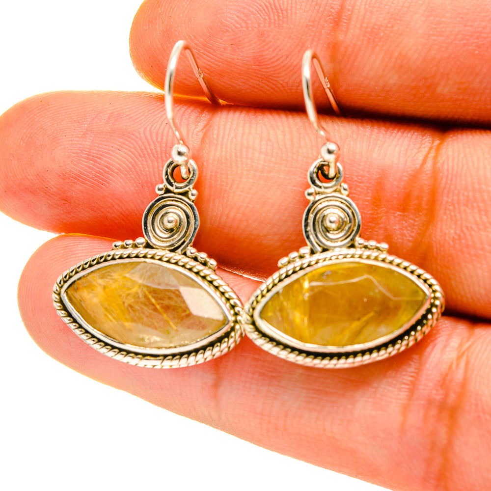 Close-up rutilated quartz oval earrings on hooks, gold-tone setting with circular accents