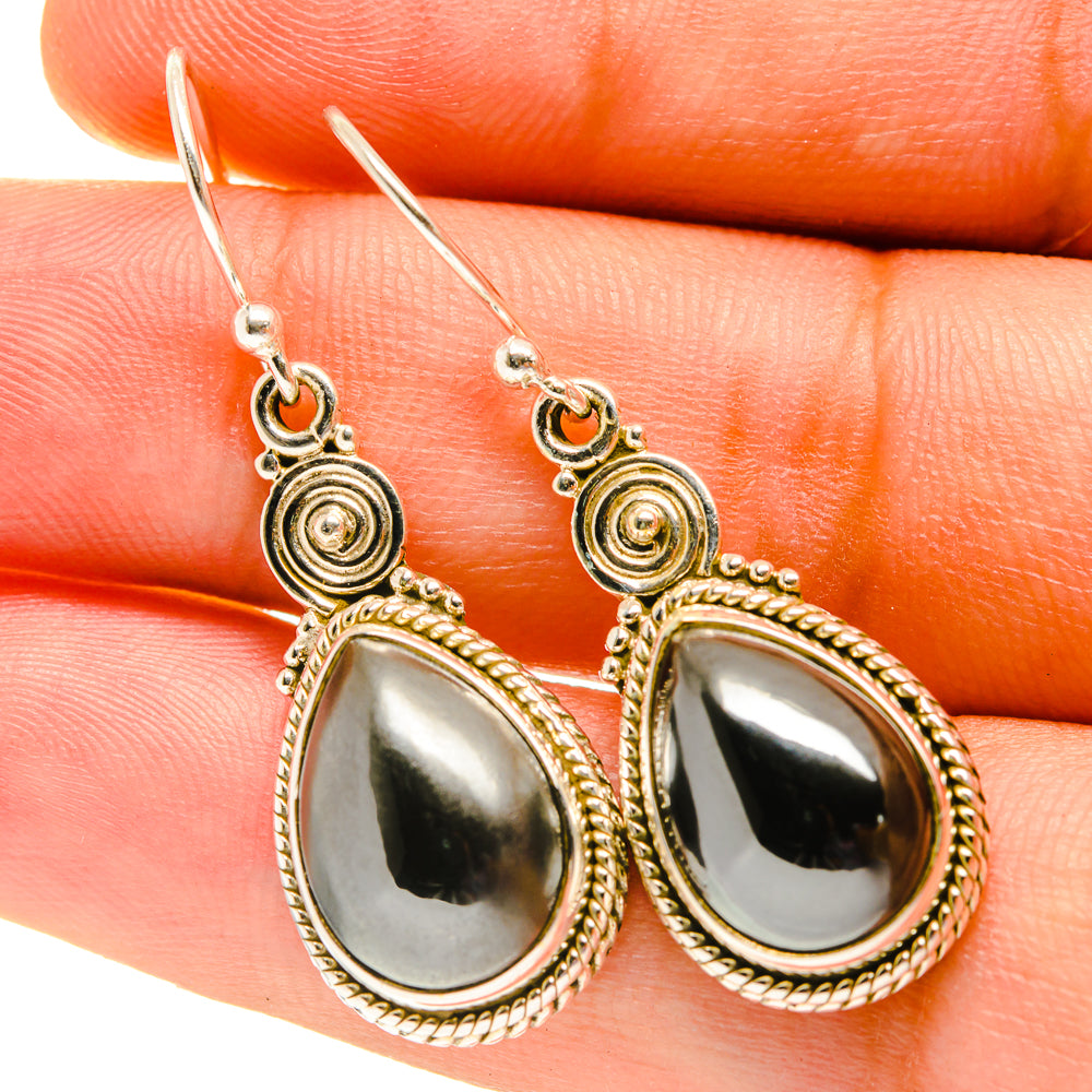 Closeup teardrop hematite earrings in gold-tone with scalloped bezel, circular details