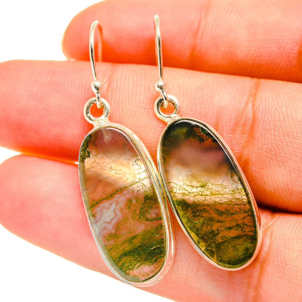 Close-up of oval green agate drop earrings with silver hooks