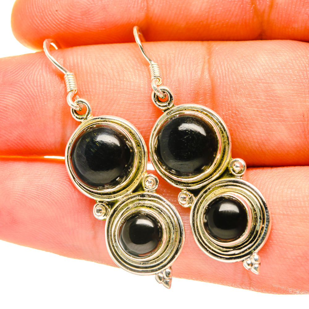 Close-up round black onyx earrings with gold-tone stacked ring settings and hooks