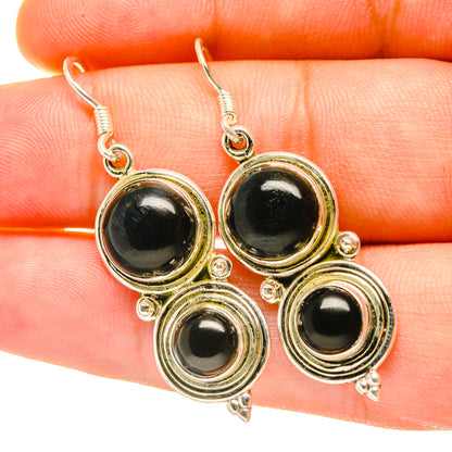 Close-up round black onyx earrings with gold-tone stacked ring settings and hooks